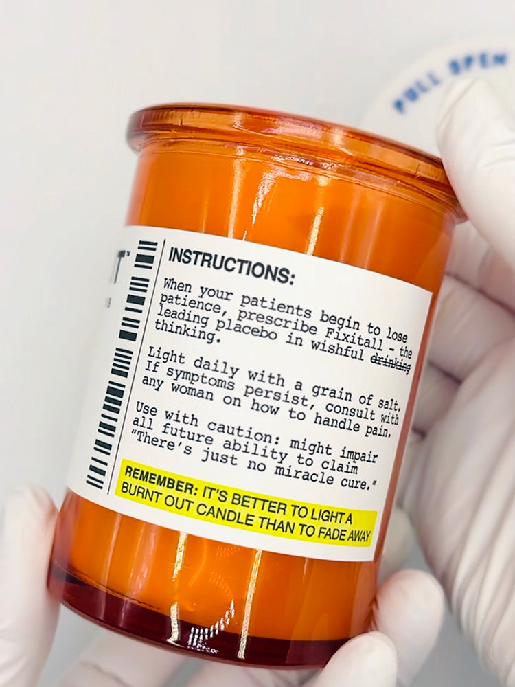 Orange candle with a label held by a gloved hand on a white background