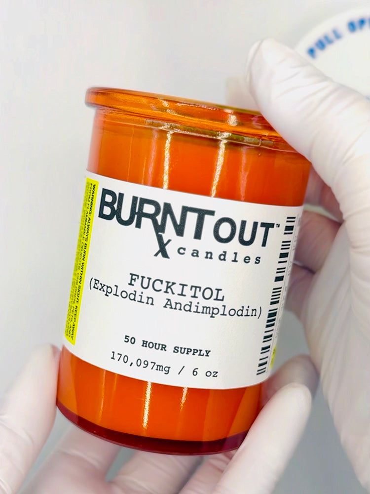 Orange candle labeled 'Burnt Out Candles' held by a gloved hand against a white background