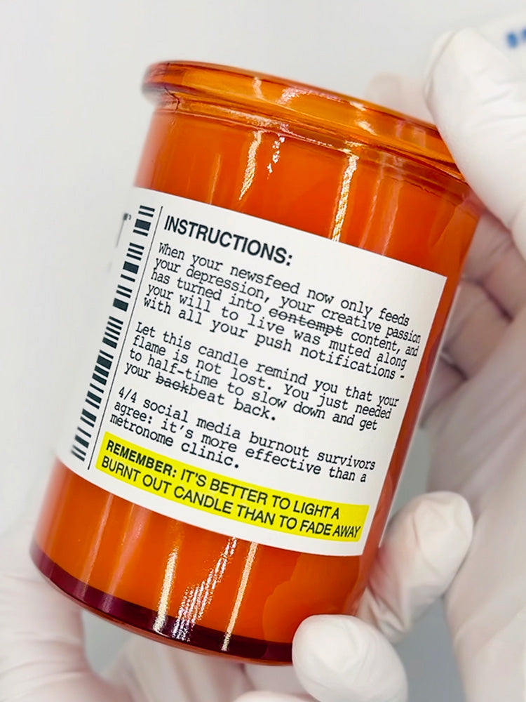 Orange candle jar with a label containing humorous instructions and text.